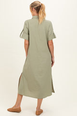 woman wearing a sage green maternity maxi dress with short sleeves and side slits