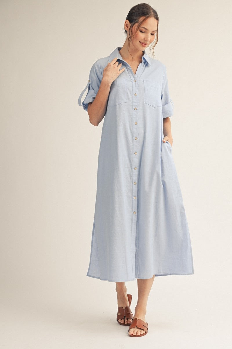 woman wearing a light blue button-up shirt dress with rolled sleeves and a relaxed fit