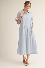 woman wearing a light blue button-up shirt dress with rolled sleeves and a relaxed fit