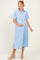 woman wearing a light blue maternity button-up dress with short sleeves and a visible baby bump