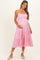 woman wearing a light pink maternity maxi dress with tiered ruffles and a baby bump, posing with one hand on her belly
