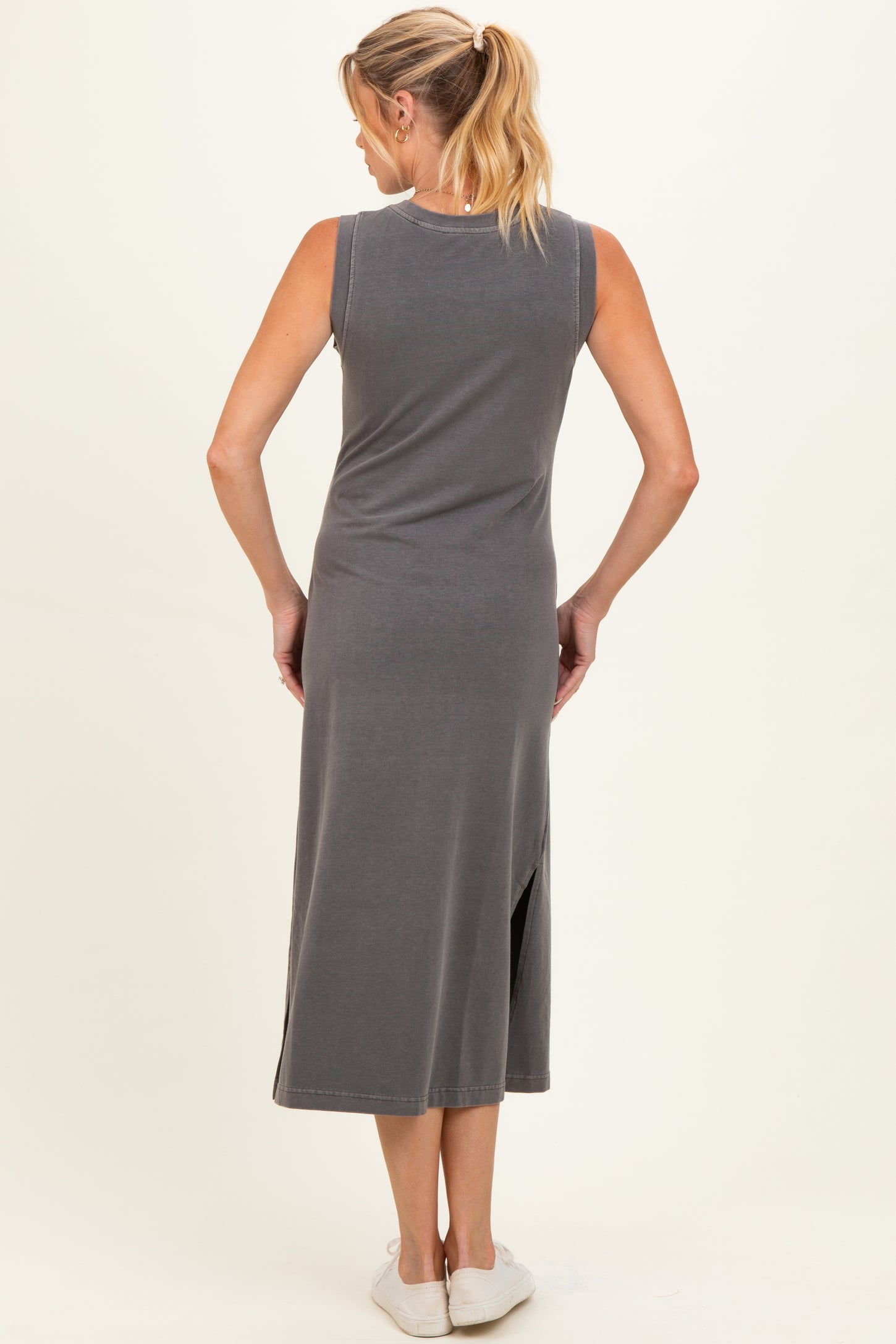 woman wearing a gray sleeveless maternity dress with a side slit, showing the back view