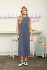 woman wearing a sleeveless long gray maxi dress and blue sneakers