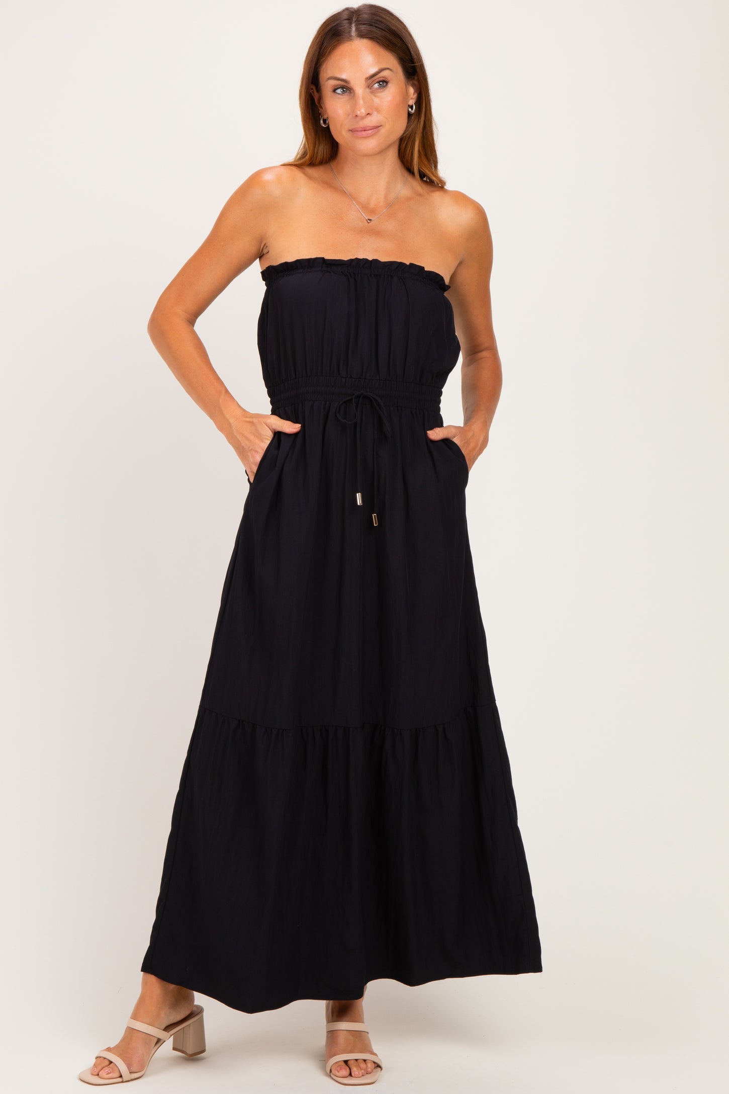woman wearing a black strapless maxi dress with a smocked bodice and pockets