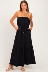 woman wearing a black strapless maxi dress with a smocked bodice and pockets