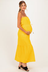 woman wearing a yellow strapless maternity maxi dress and holding her baby bump