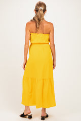 woman wearing a bright yellow strapless maternity maxi dress with a tiered skirt and elastic waistband