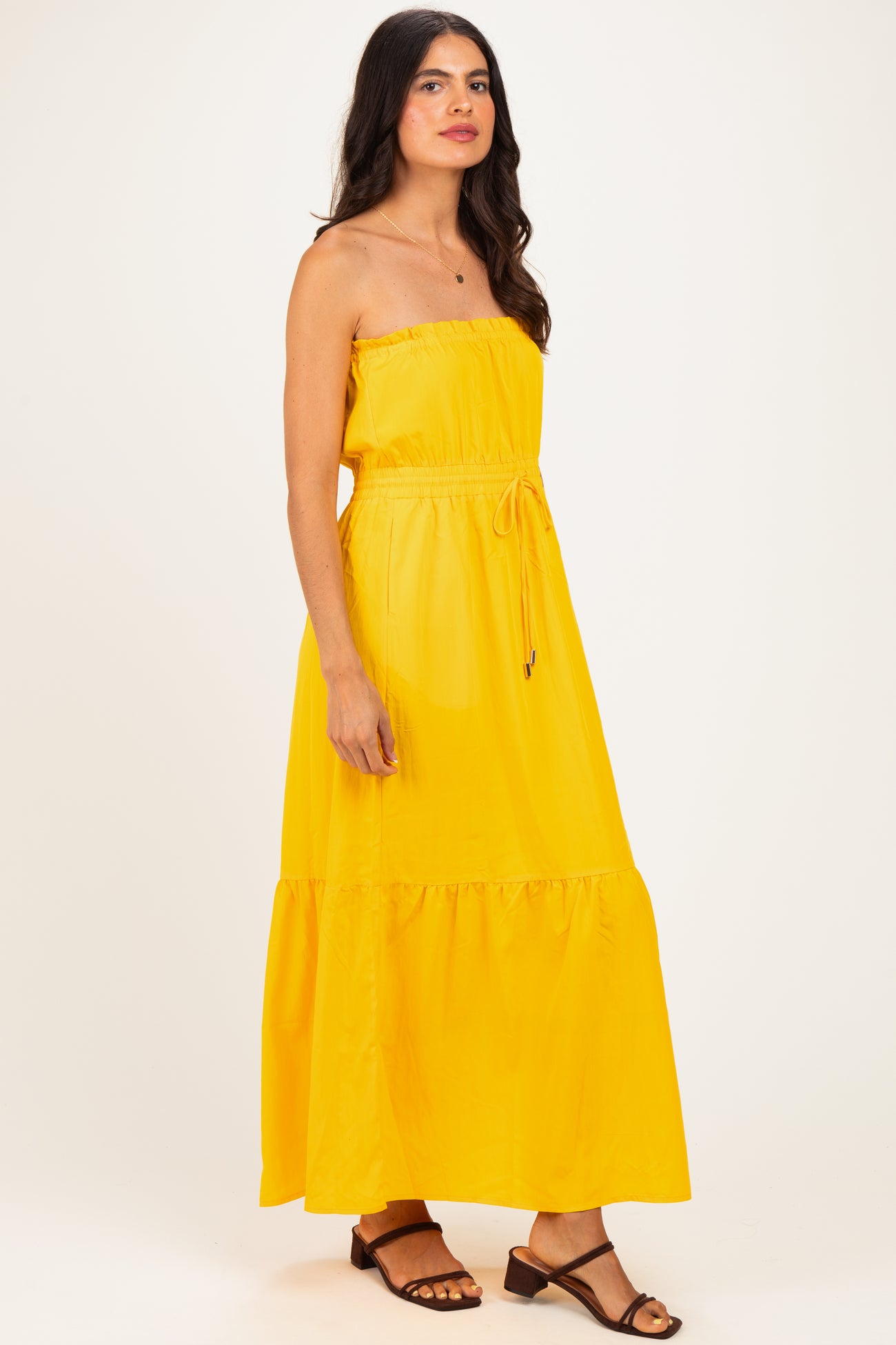 woman wearing a yellow strapless maxi dress with an elastic waist and ruffle hem