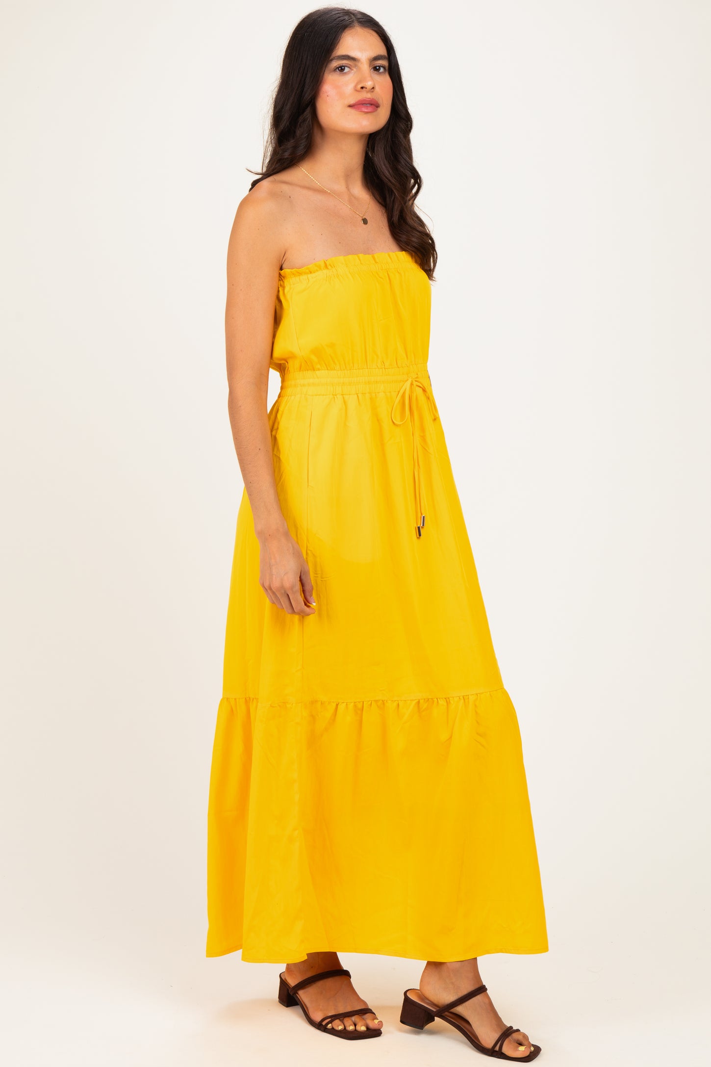 woman wearing a yellow strapless maxi dress with an elastic waist and ruffle hem