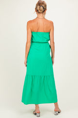 woman wearing a strapless green maternity maxi dress with a tiered hem and an elastic waistband