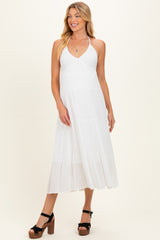 woman wearing a white halter neck maternity dress with tiered skirt and black platform sandals, baby bump not visible