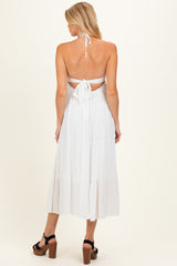 woman wearing a white maternity dress with a halter neck and tied back, showcasing a flowing silhouette