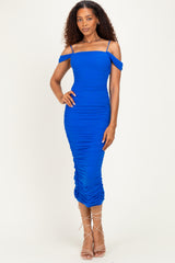 woman wearing a bright blue off-shoulder ruched bodycon dress with a fitted silhouette