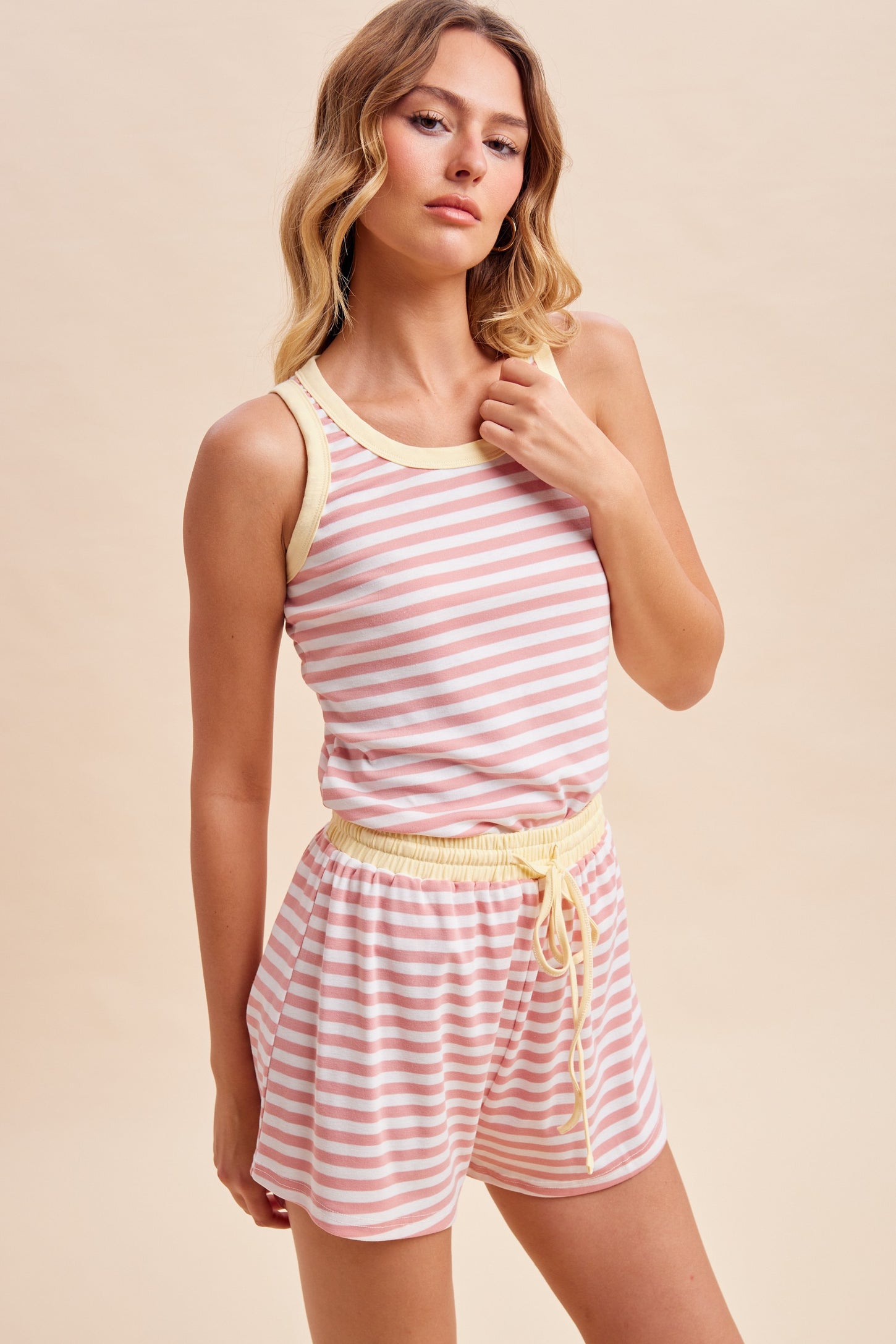 woman wearing a pink and white striped tank top and matching shorts with a yellow waistband