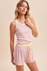 woman wearing a pink and white striped tank top and matching shorts with a yellow waistband