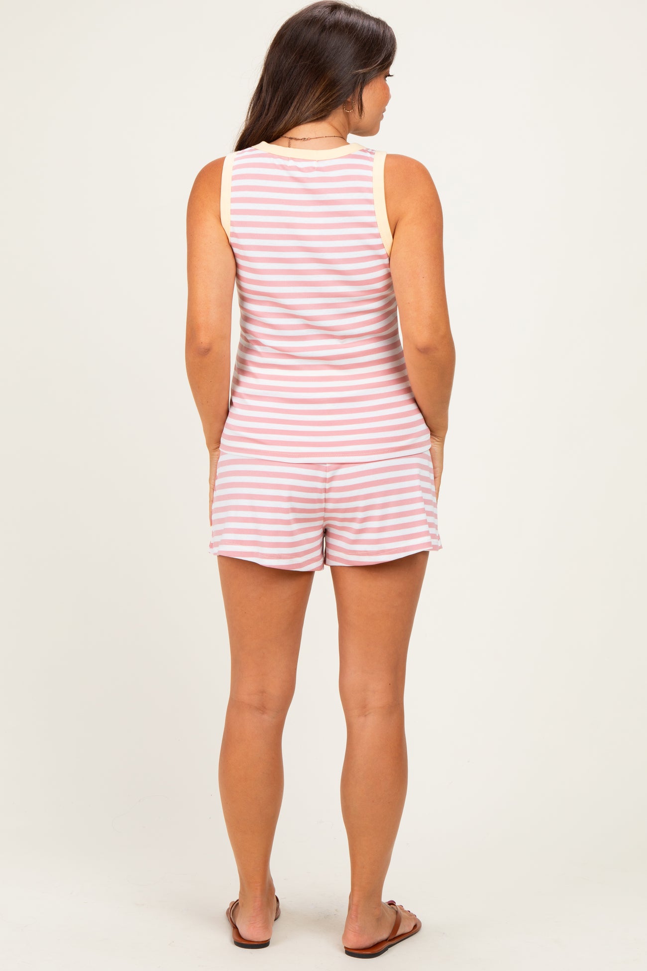 woman wearing a striped maternity romper with a sleeveless design, showing the back view