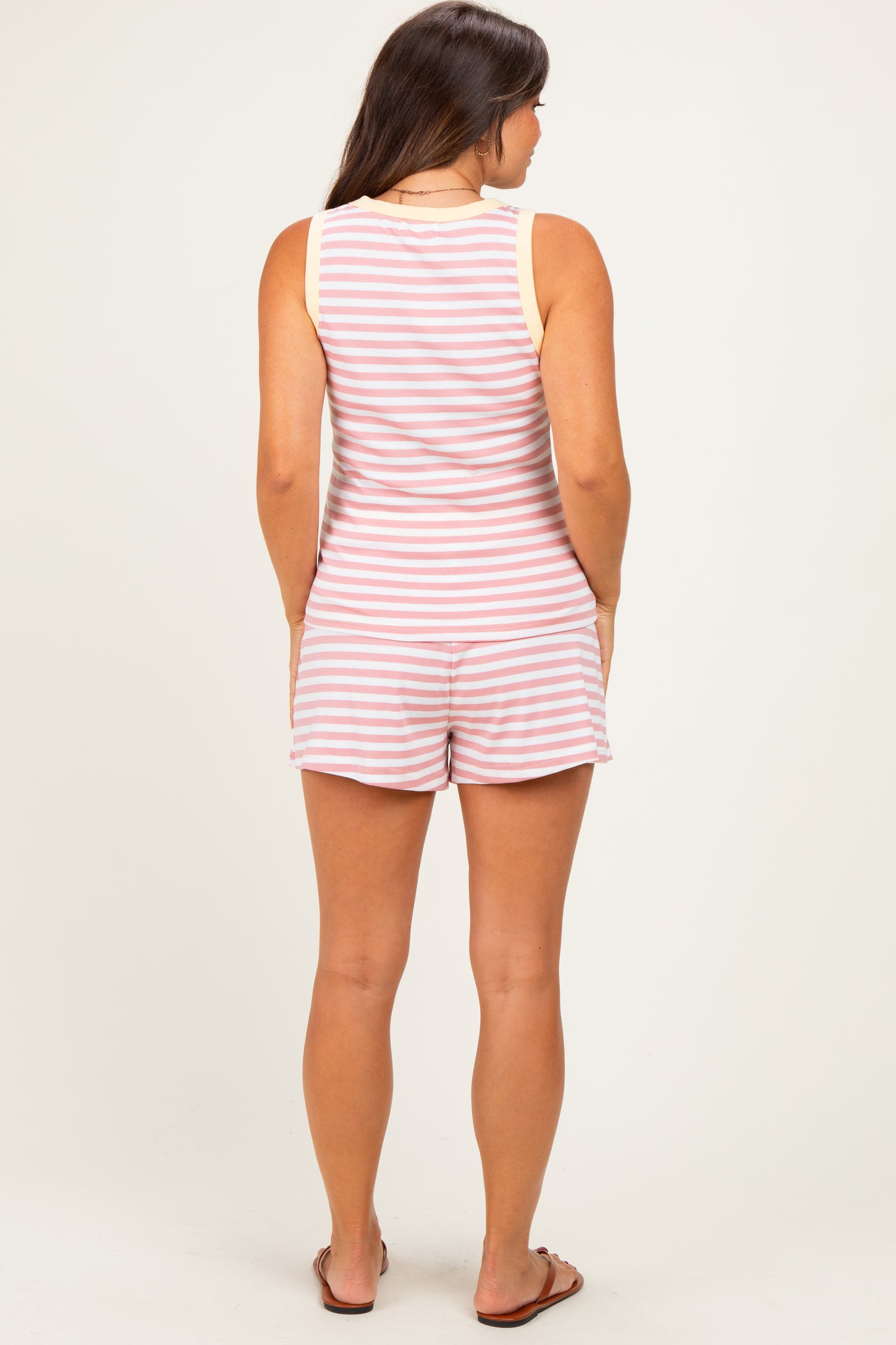 woman wearing a striped maternity romper with a sleeveless design, showing the back view