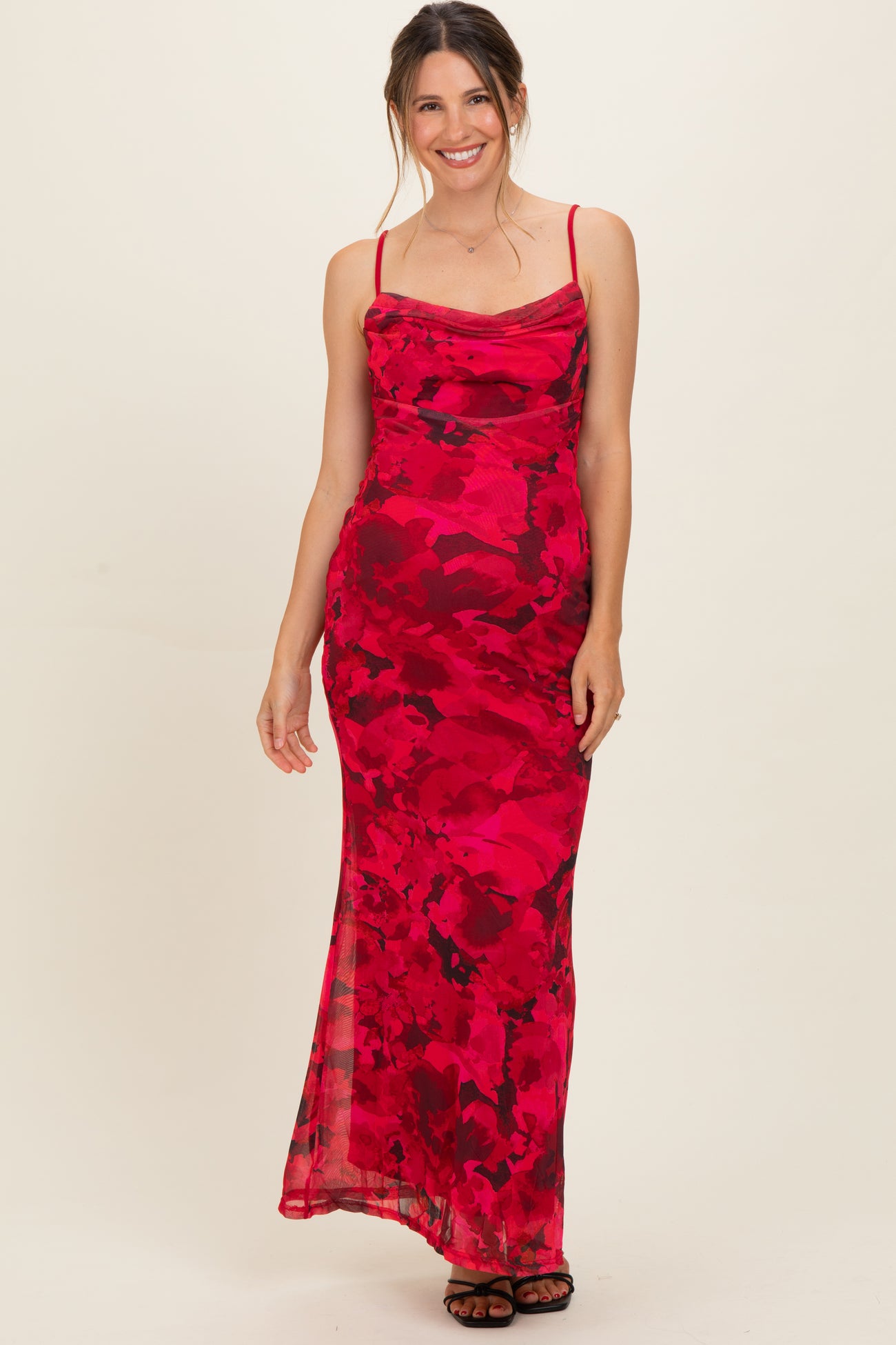 woman wearing a red floral print maternity dress with spaghetti straps and a fitted silhouette, showcasing her baby bump