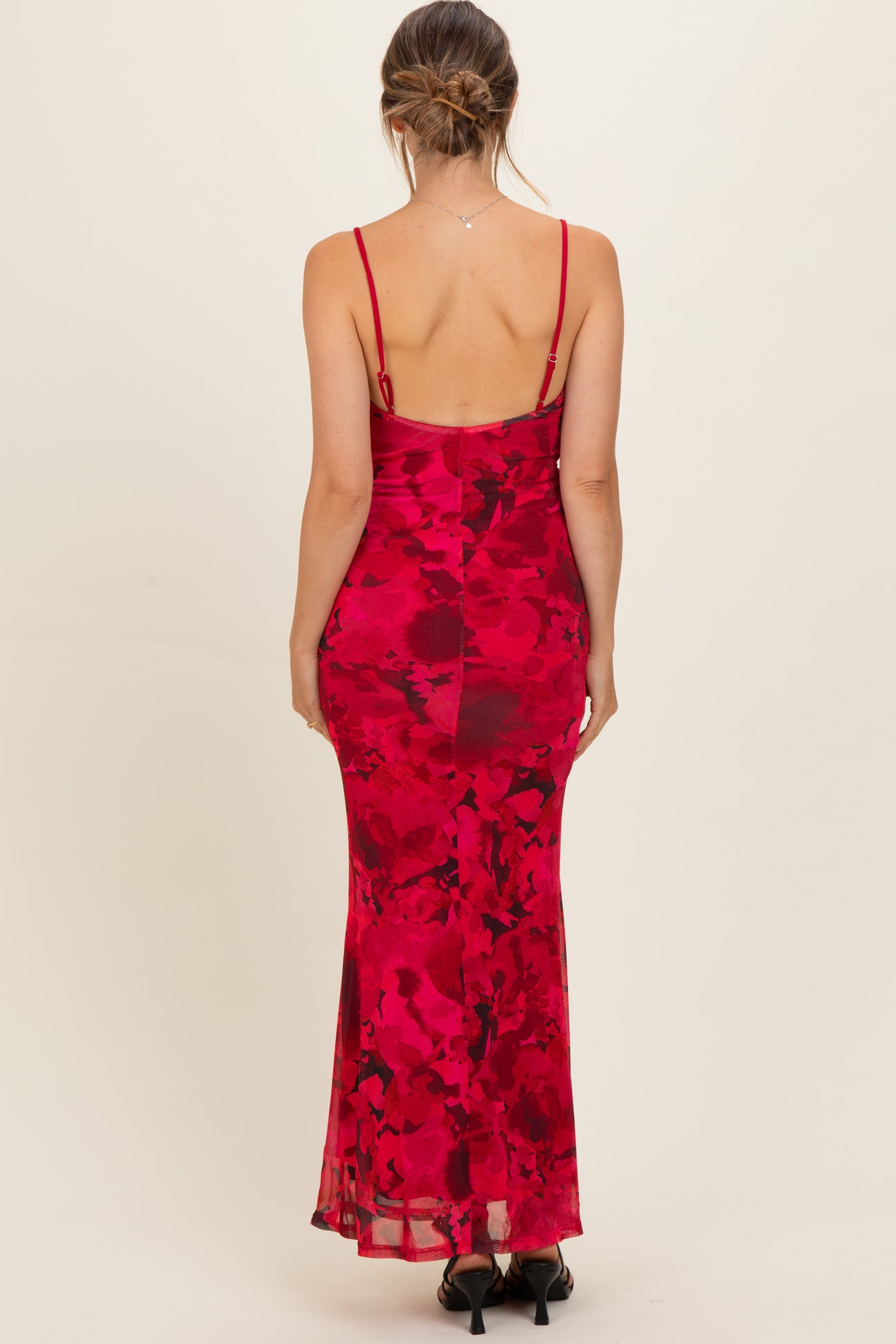woman wearing a red floral maternity dress with a fitted silhouette and spaghetti straps