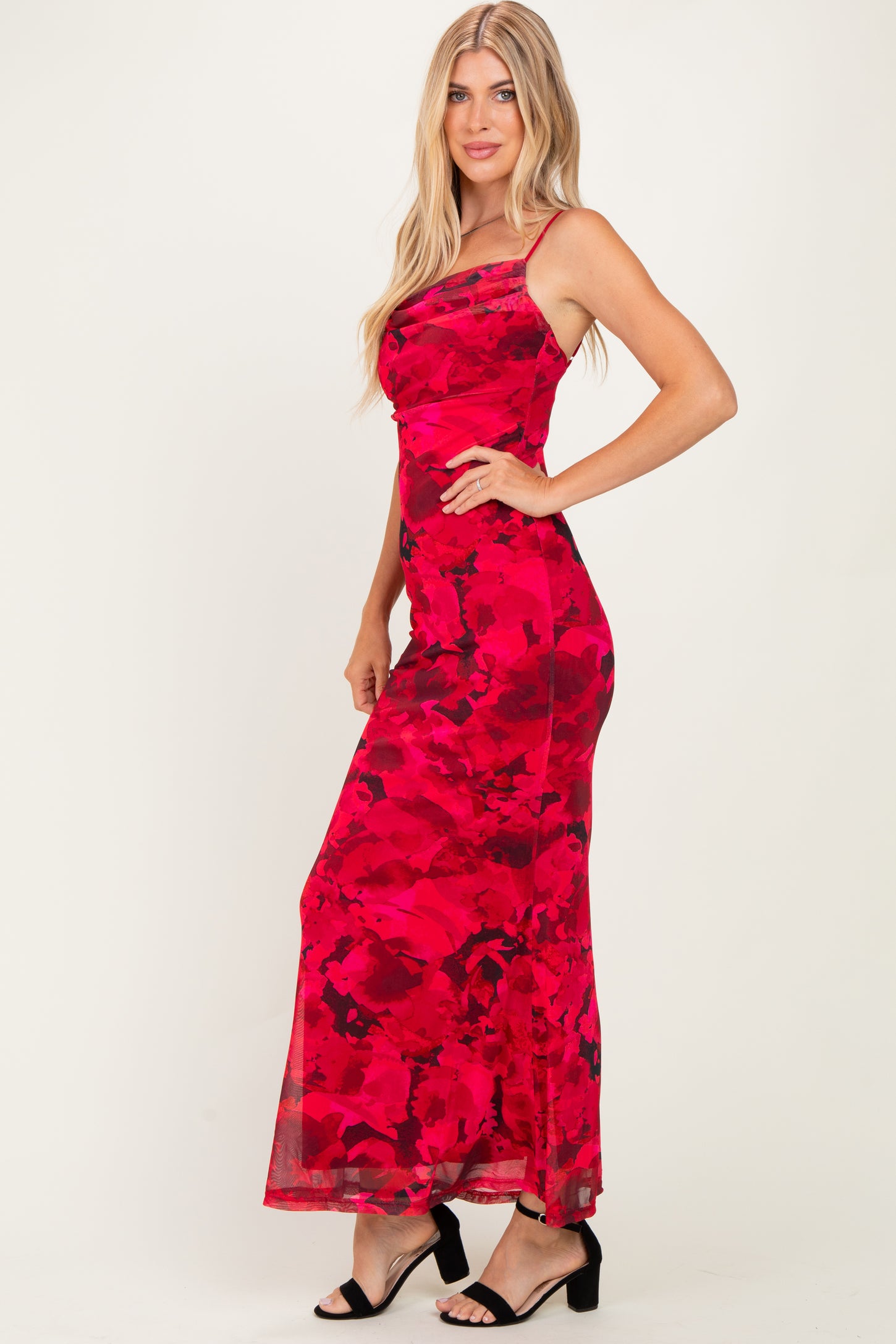 woman wearing a red floral maxi dress with a fitted silhouette and spaghetti straps, standing sideways