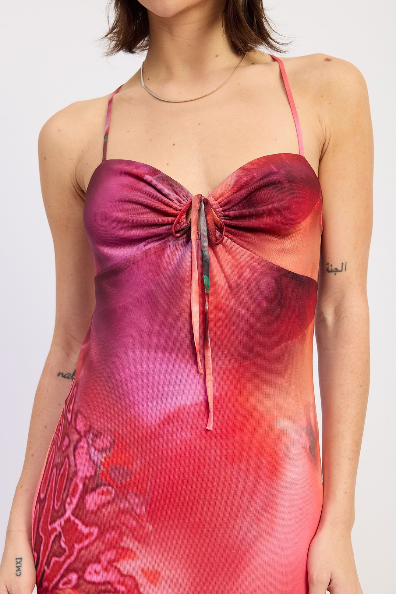 woman wearing a vibrant pink and red tie-front dress with thin straps and a floral design