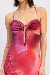 woman wearing a vibrant pink and red tie-front dress with thin straps and a floral design