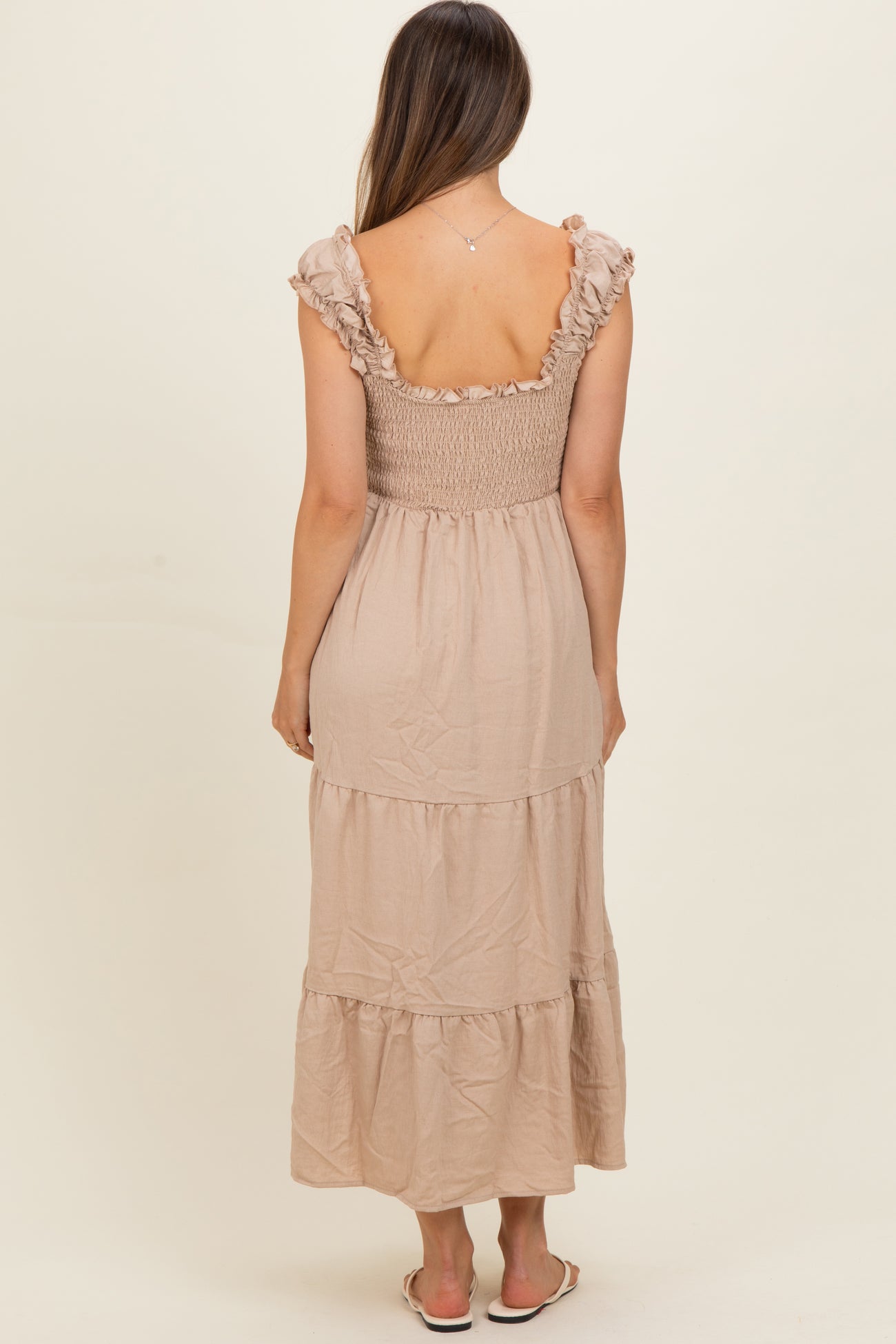 woman wearing a beige maternity maxi dress with a smocked bodice and ruffled sleeves