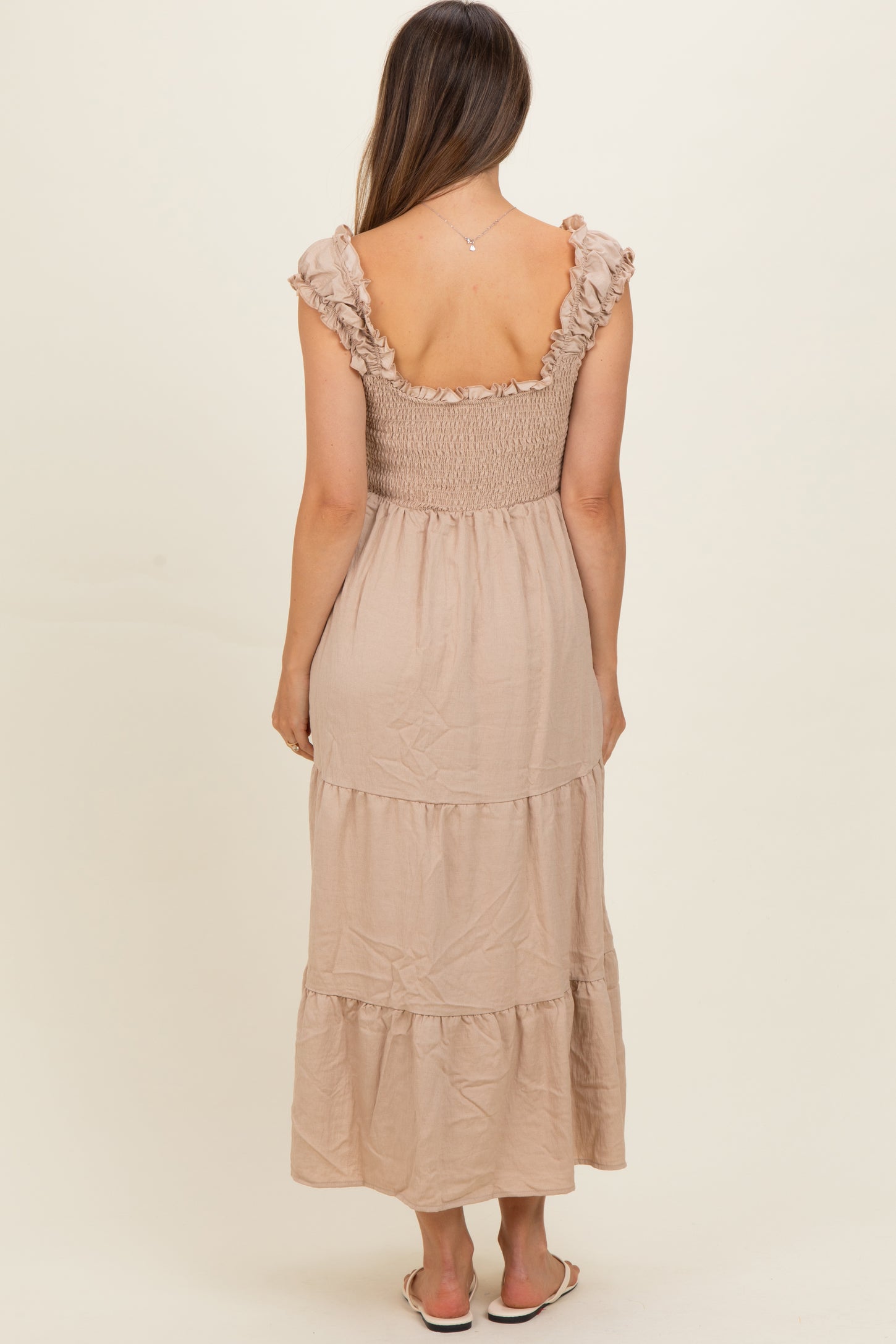 woman wearing a beige maternity maxi dress with a smocked bodice and ruffled sleeves