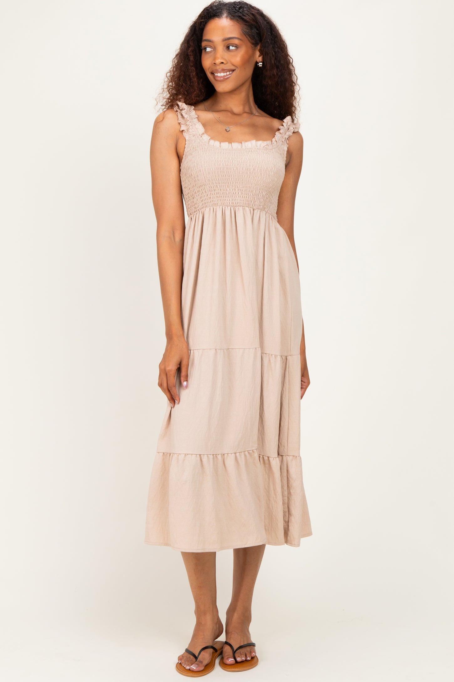 woman wearing a light beige smocked maxi dress with ruffle straps and a tiered skirt