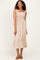woman wearing a light beige smocked maxi dress with ruffle straps and a tiered skirt
