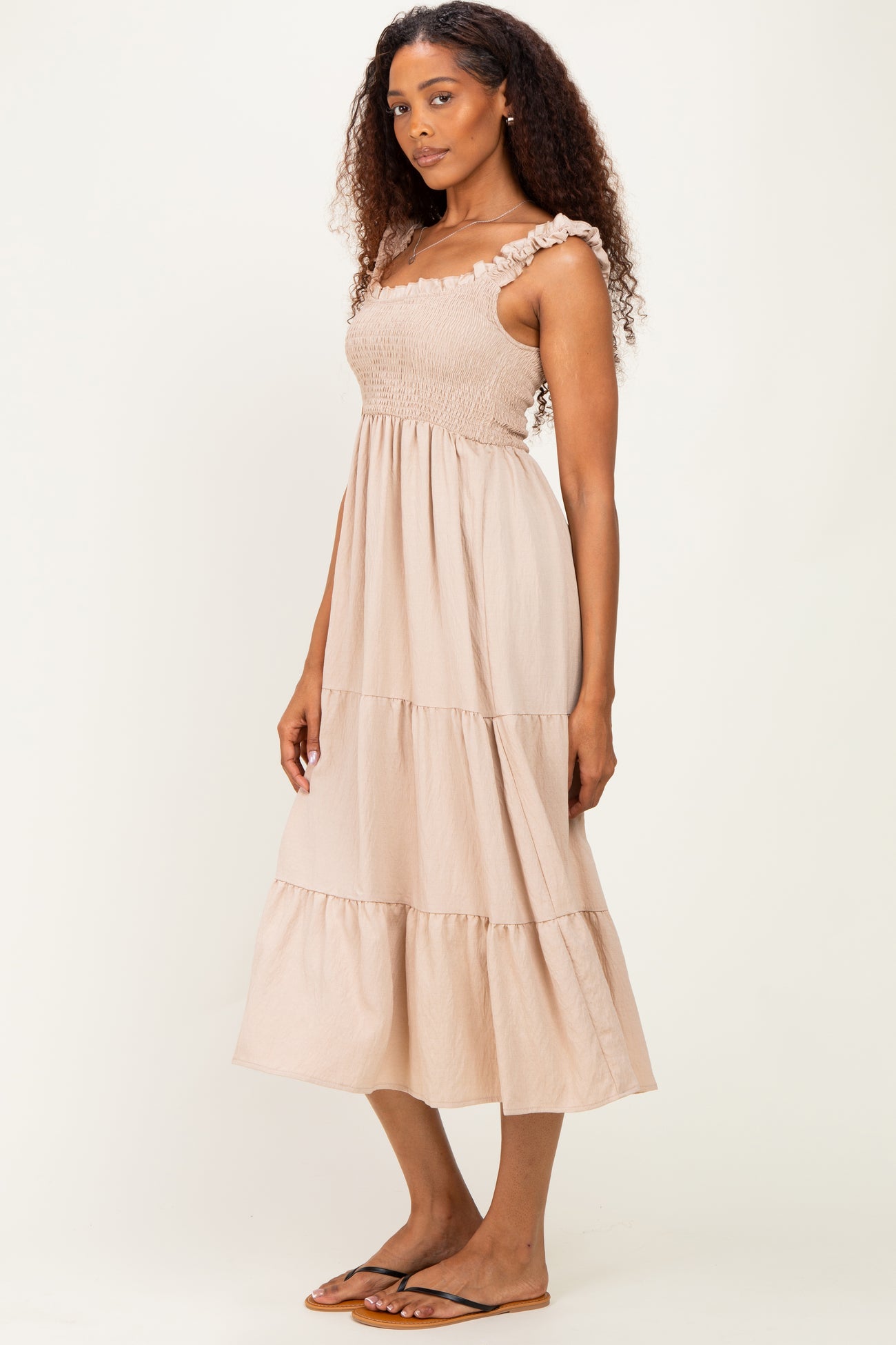 woman wearing a beige tiered maxi dress with ruffle straps and smocked bodice, standing sideways