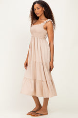 woman wearing a beige tiered maxi dress with ruffle straps and smocked bodice, standing sideways