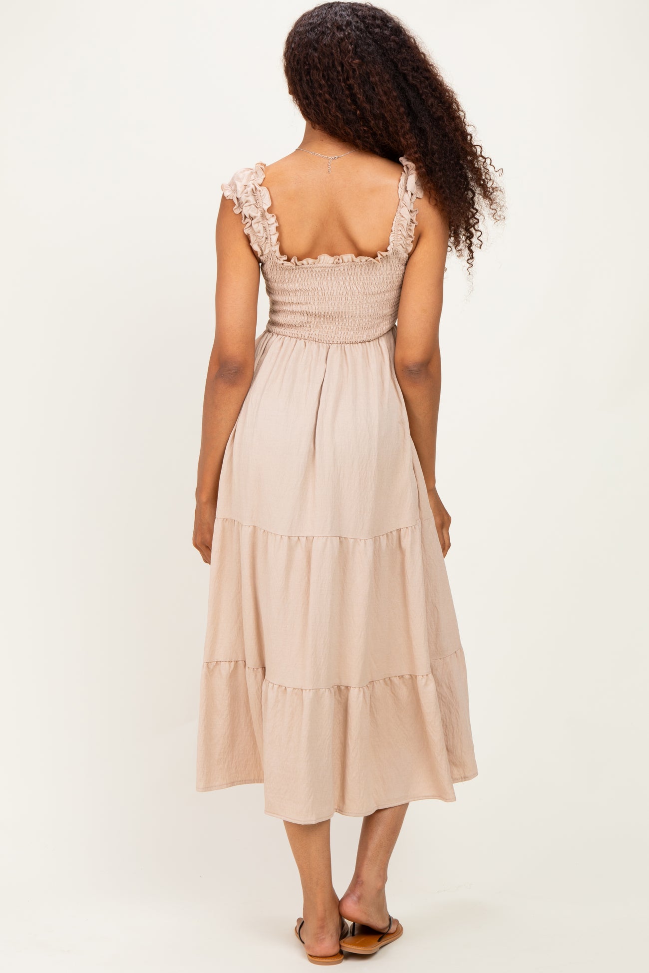 woman wearing a light beige tiered maxi dress with smocked bodice and ruffle straps