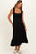 woman wearing a black maternity dress with smocked bodice and tiered skirt, featuring ruffle straps and a flowing style