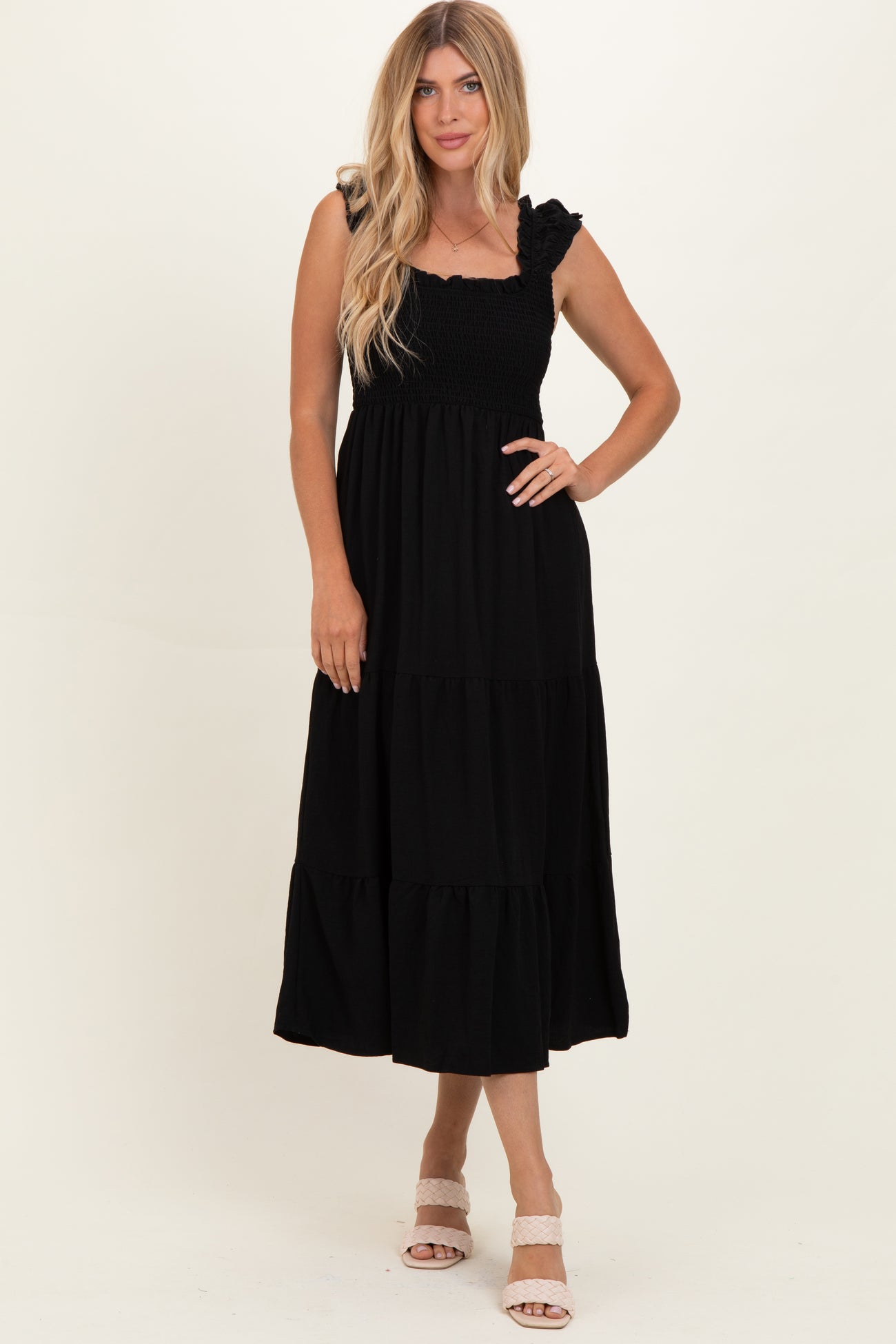 woman wearing a black tiered maxi dress with ruffled straps and a smocked bodice