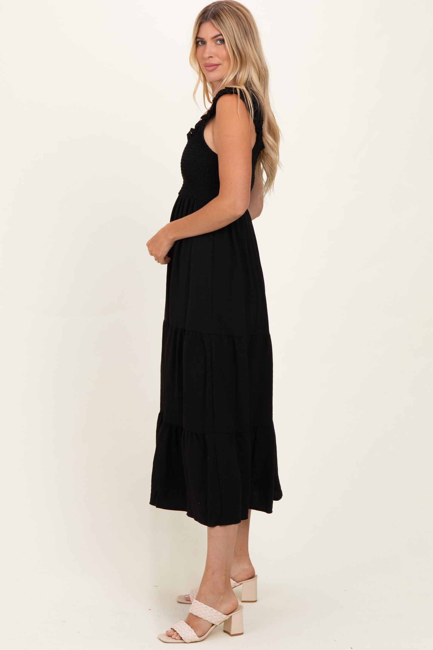 woman wearing a black tiered maxi dress with a smocked bodice and ruffled straps, standing sideways