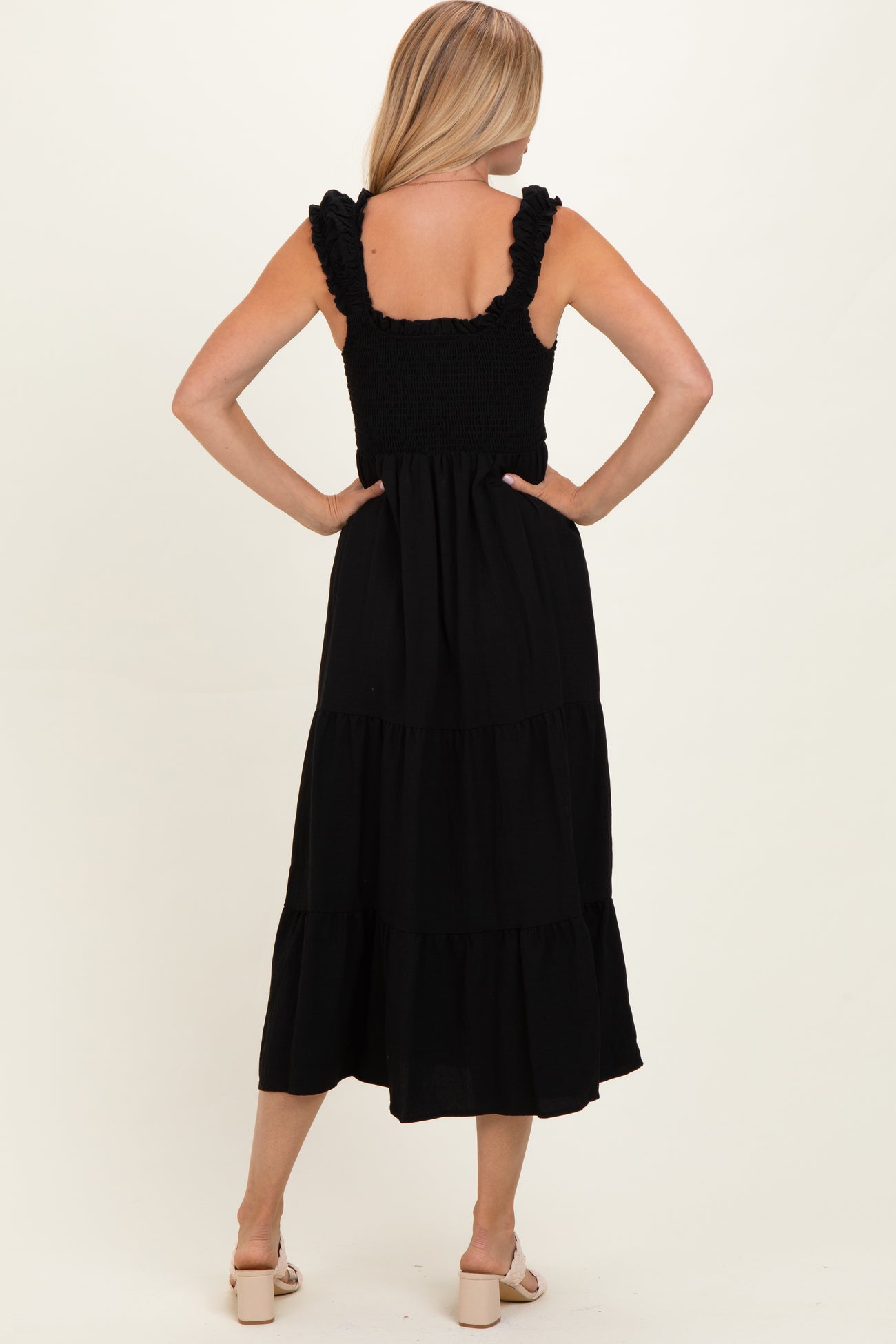 woman wearing a black tiered maxi dress with ruffled straps and a smocked bodice, viewed from the back
