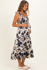 woman wearing a blue and white floral print maternity dress with ruffled straps and a visible baby bump