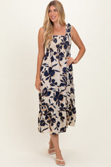 woman wearing a floral print maxi dress with navy blue flowers on a cream background and ruffled straps