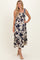 woman wearing a floral print maxi dress with navy blue flowers on a cream background and ruffled straps