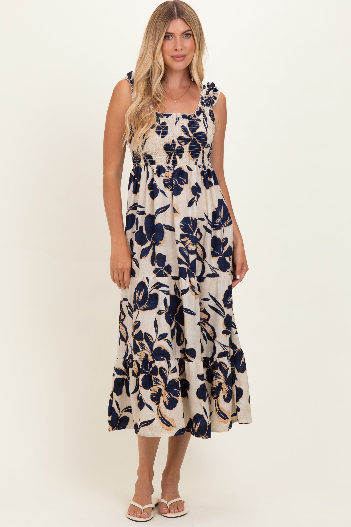woman wearing a cream midi dress with navy floral print and ruffled straps