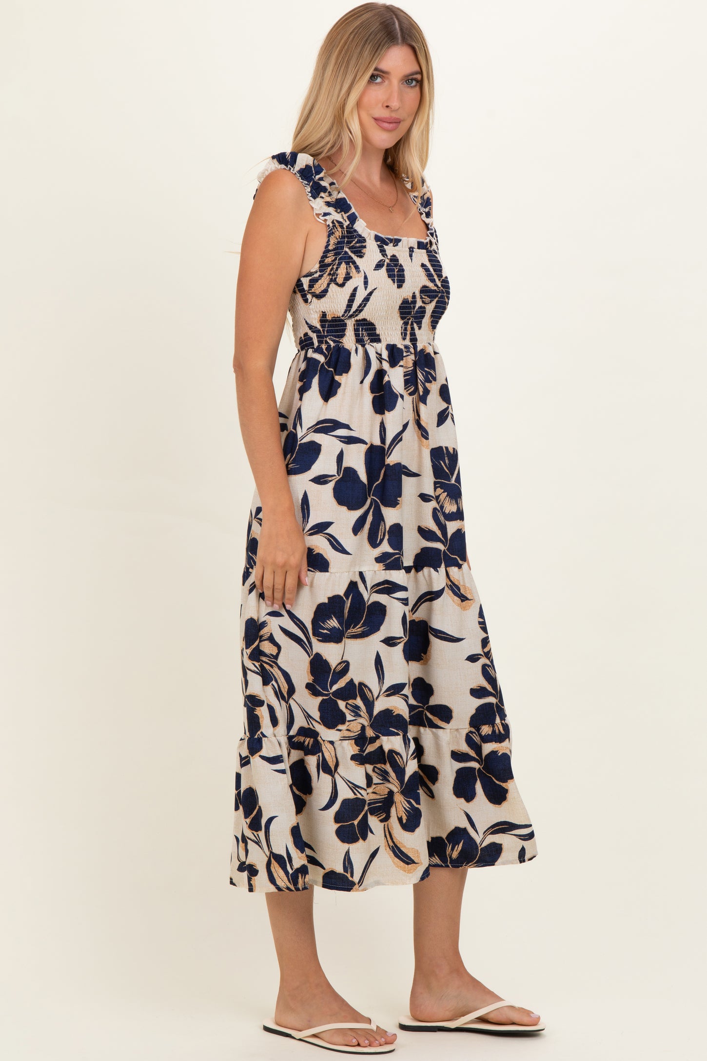 woman wearing a floral print maxi dress with blue and beige colors and ruffled straps