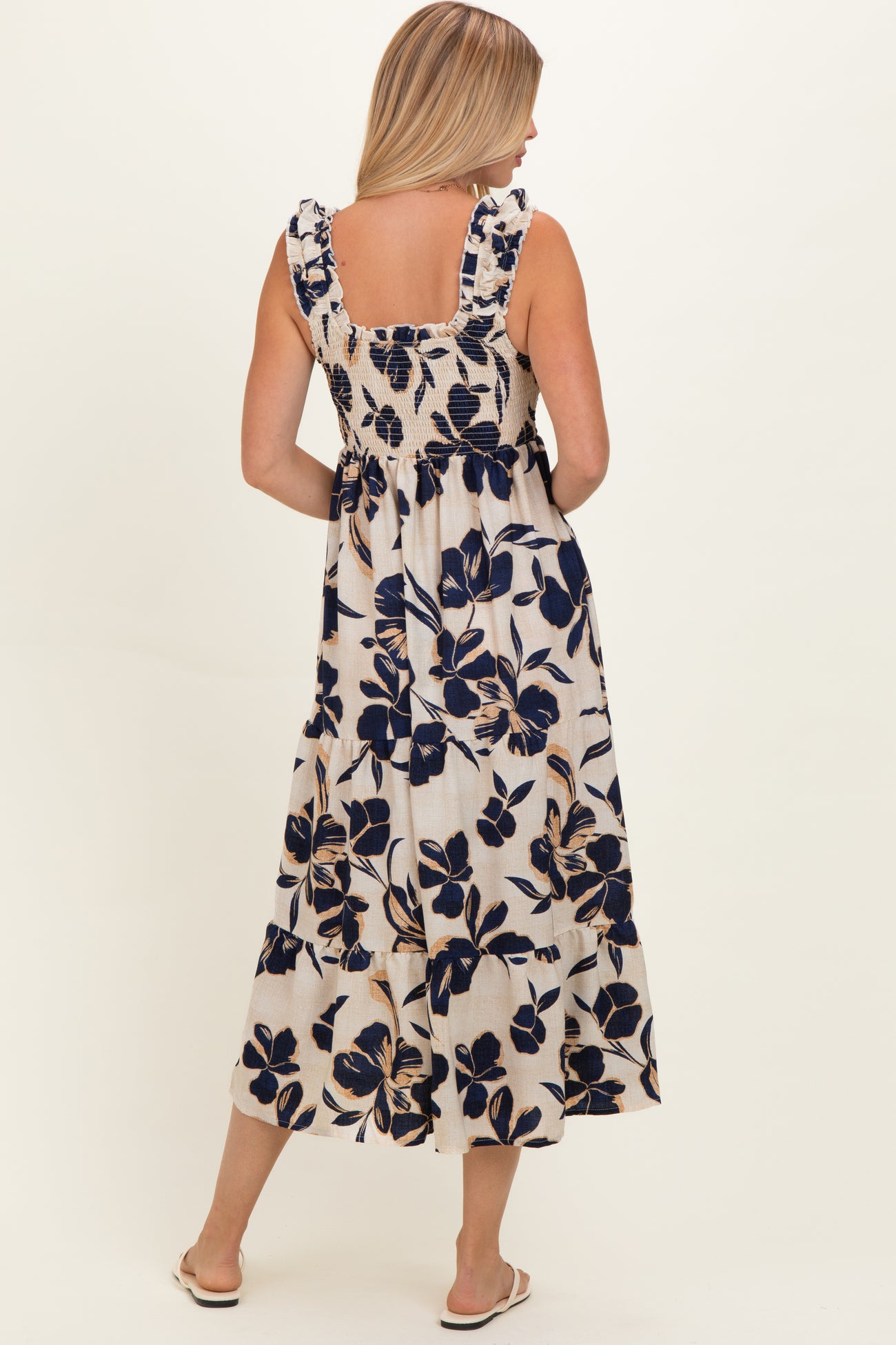 woman wearing a floral print maxi dress with ruffled straps and a smocked bodice, viewed from the back