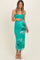 woman wearing a teal floral maternity dress with a fitted silhouette and spaghetti straps, holding her baby bump