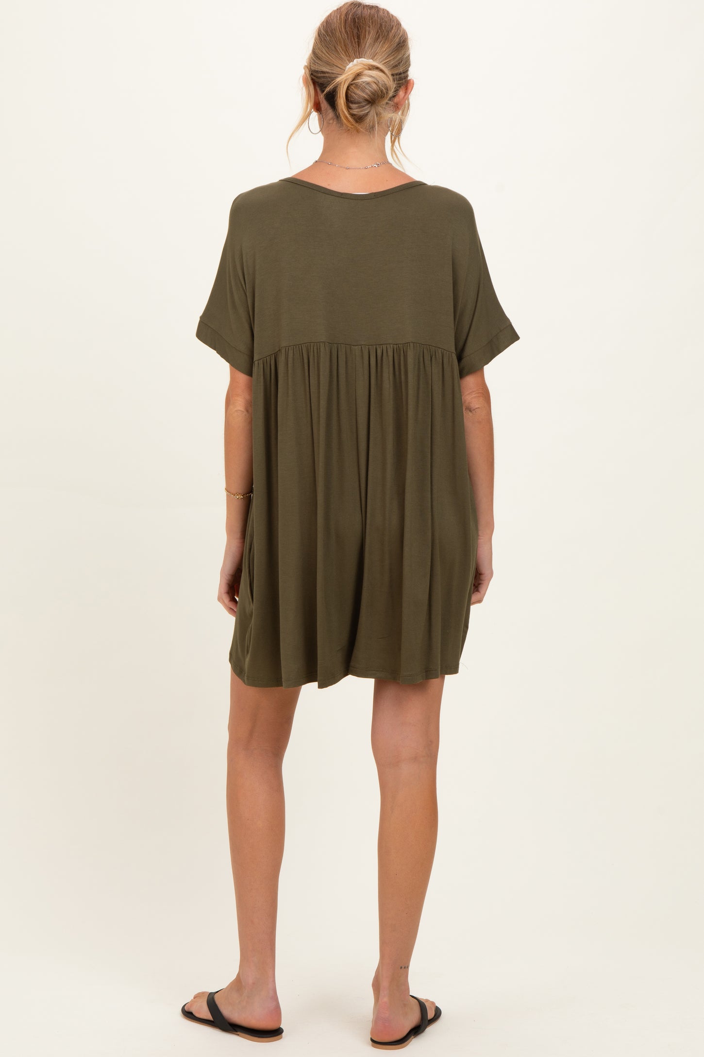 woman wearing an olive green maternity dress with a loose fit and short sleeves, back view, showing a flowing silhouette