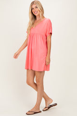 woman wearing a vibrant coral short sleeve dress with a relaxed fit and empire waistline