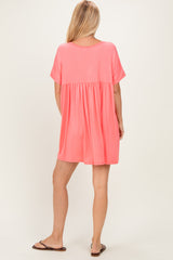 woman wearing a relaxed fit coral short sleeve dress with a tiered skirt and a scoop back