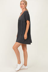 woman wearing a dark gray short sleeve v-neck dress with a flared hem and white sneakers