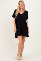 woman wearing a black short sleeve swing dress with a v-neck and relaxed fit