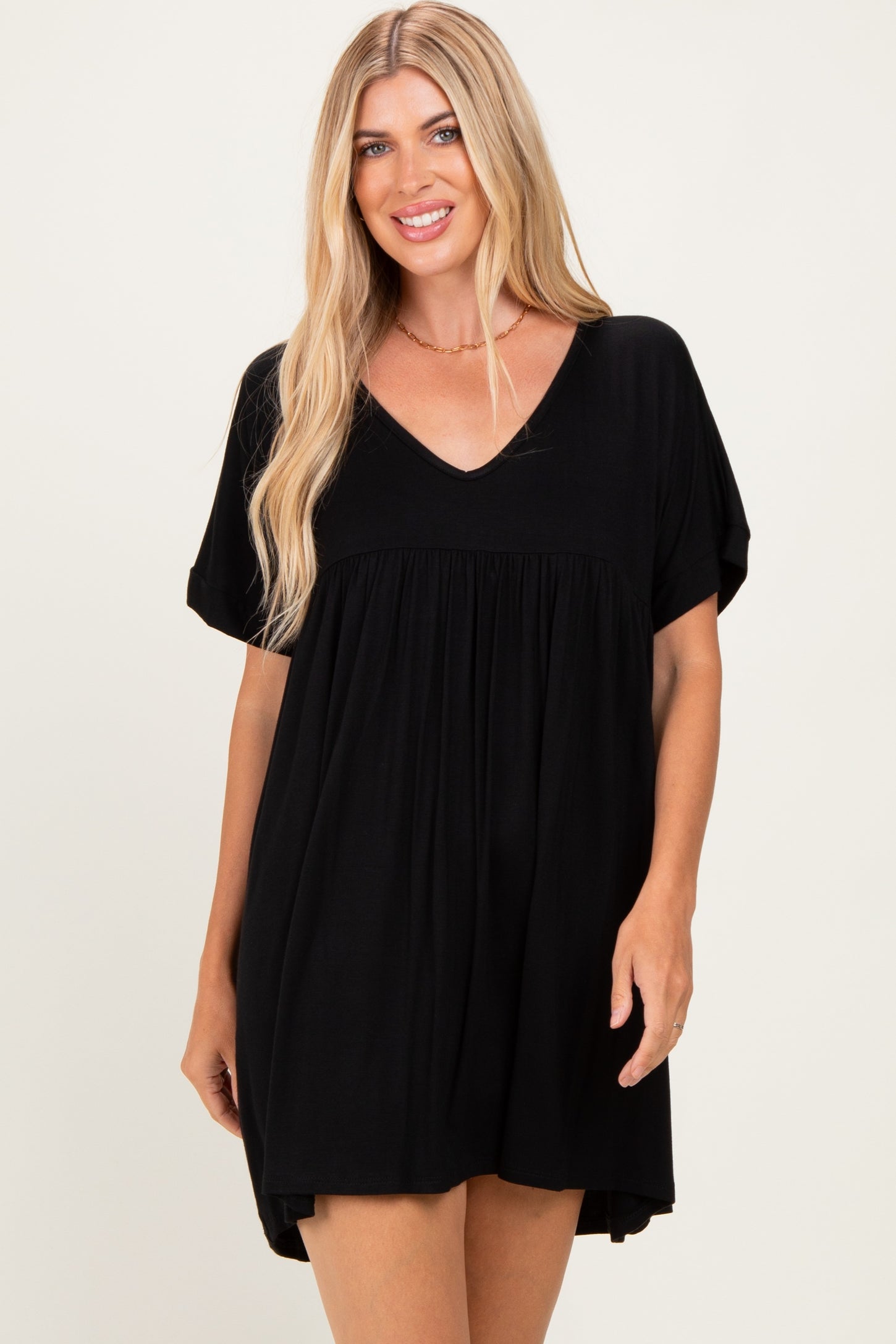 woman wearing a black short sleeve v-neck dress with a flared silhouette and relaxed fit